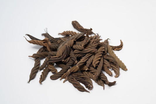 A photo of a pile of Twisty Pods. They are brown textured seed pods on a white background.