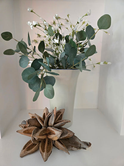 Vase with greenery and dried plant on a white background