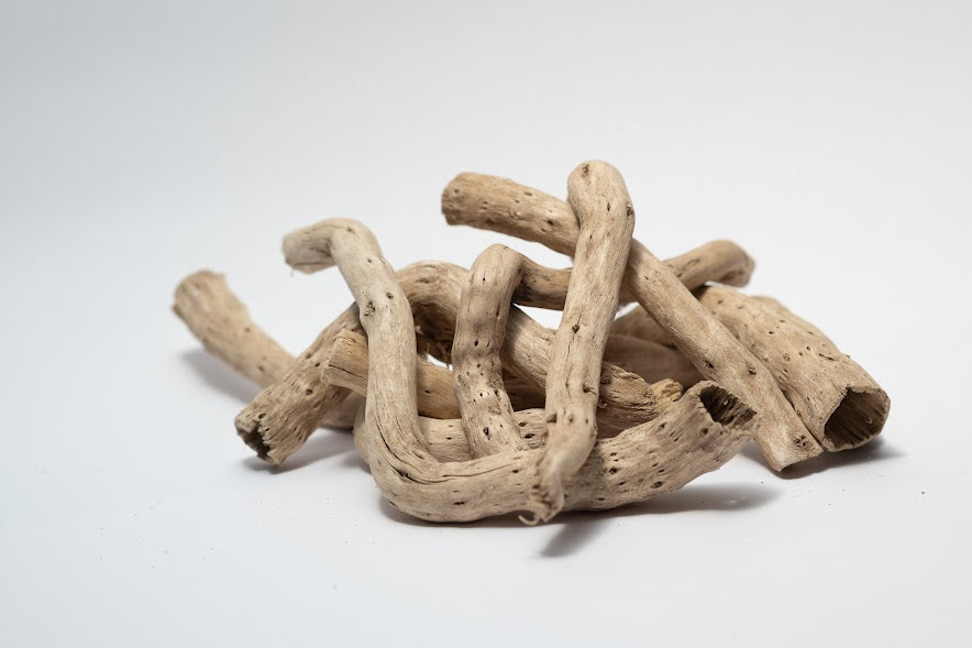 A photo of a pile of Dried Cabbage Roots. They are light brown and smooth roots on a white background.