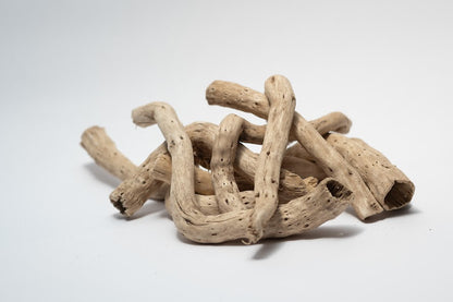 A photo of a pile of Dried Cabbage Roots. They are light brown and smooth roots on a white background.