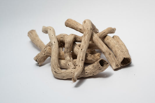 A photo of a pile of Dried Cabbage Roots. They are light brown and smooth roots on a white background.
