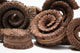 A close up photo of a pile of Palm Tail Spring. They are brown textured spiral shaped botanical on a white background.