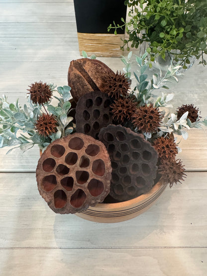Bowl with lotus seeds and greenery on a wooden surface