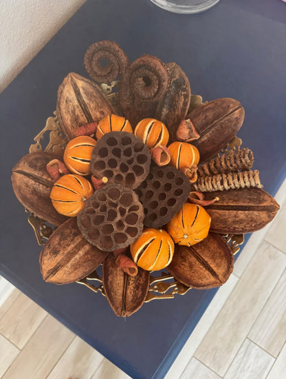 Decorative arrangement of nuts and dried oranges in a gold bowl.