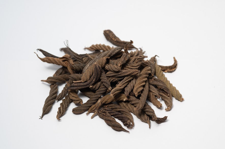 A photo of a pile of Twisty Pods. They are brown textured seed pods on a white background.