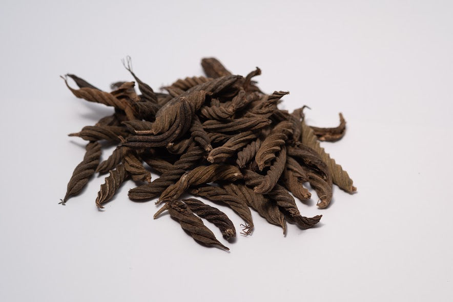A photo of a pile of Twisty Pods. They are brown textured seed pods on a white background.