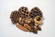 Dried botanical seed pods in a pile showing the array of shades of brown and textures.  Displayed on a white background.