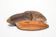Three triangle pods laying horizontal showing the dark brown top of the pod and the light brown bottom of the seed pod on a white background.